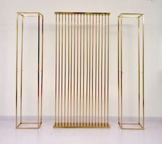 three tall gold metal stands against a white wall