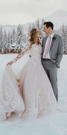 a bride and groom standing in the snow