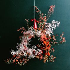 an arrangement of flowers on a black background with a red bow hanging from the top