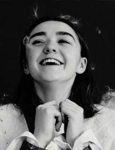 a black and white photo of a woman with her hands on her neck, smiling