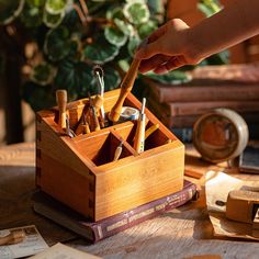 a wooden box filled with lots of pens and pencils on top of a table