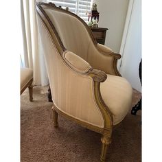 an old fashioned chair sitting on top of a carpeted floor next to a window