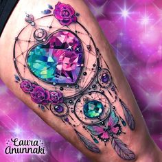 a woman's leg with an intricate tattoo design on it and pink roses, blue crystals