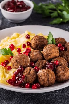 meatballs and mashed potatoes on a plate with cranberry sauce in the background