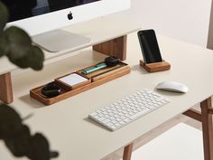 a computer desk with a keyboard, mouse and cell phone