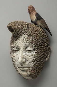 a bird sitting on top of a statue of a person's head with a bird perched on it