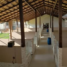 the inside of a building with several stalls lined up on either side and two blue trash cans sitting in front of them