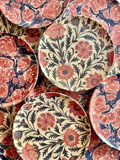 several red and blue plates sitting on top of each other with designs on the sides