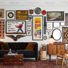 a living room filled with furniture and lots of framed pictures on the wall above it