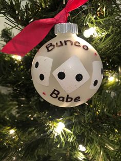 a christmas ornament that says bunco babe on it's face and is hanging from a tree