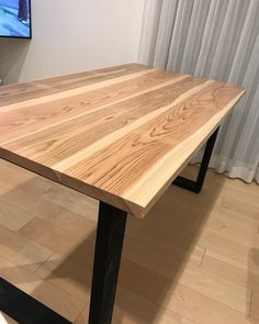 a wooden table sitting on top of a hard wood floor next to a white wall