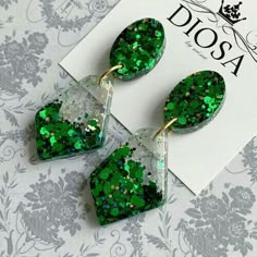 green glitter heart shaped earrings on top of a card