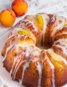 a white plate topped with a bundt cake covered in icing and peaches