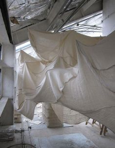 an unfinished room with white sheets hanging from the ceiling