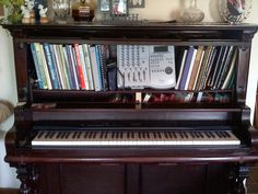 an old piano is sitting in front of a shelf full of books