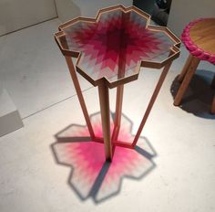 two tables with pink and white designs on them in the middle of a floor area