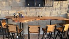 a wooden table with four stools in front of it and a brick wall behind it