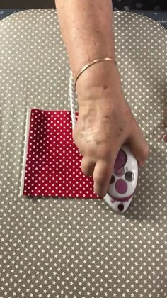 a person's hand on top of a red and white polka dot covered object