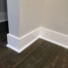 the corner of a room with wood floors and white walls