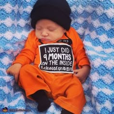 a baby wearing an orange shirt and black hat is laying on a blue blanket with the words, i just did a months down the inside