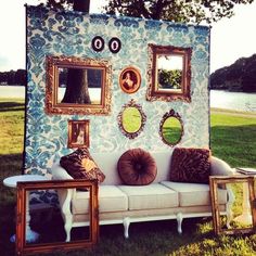 a couch sitting on top of a grass covered field next to a tree and some mirrors