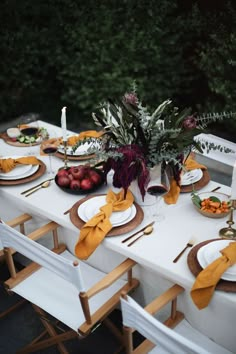 the table is set with plates, silverware, and gold napkins for dinner