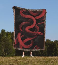 a person standing in front of a red and black blanket with a snake on it