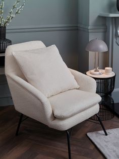 a living room with a chair, lamp and rug on the floor in front of it