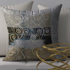 two decorative pillows sitting on top of a white couch next to a golden table and chair