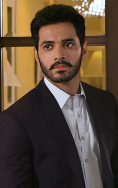 a man wearing a suit and tie standing in front of a window