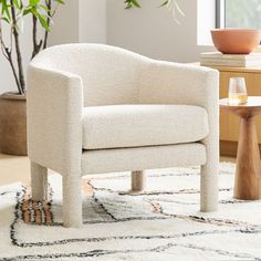 a white chair sitting on top of a rug next to a potted plant