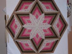 a pink and brown quilt is hanging on the wall