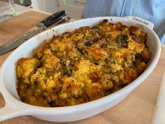 a casserole dish on a wooden table with a knife in the back ground