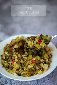 a white bowl filled with chopped green vegetables and topped with red peppers on a gray surface