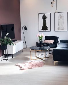 a living room filled with black furniture and pictures on the wall next to a coffee table