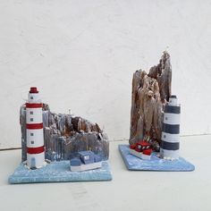 two small lighthouses are sitting next to each other on a table with a white wall in the background