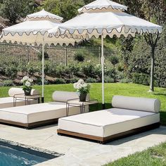 an outdoor patio with lounge chairs and umbrellas next to a swimming pool in the backyard