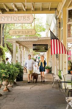 two people are walking down the sidewalk in front of an antique jewelry store with american flags