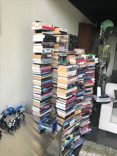 a pile of books sitting on top of a metal table next to a white chair