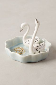 a swan shaped dish with two rings in it