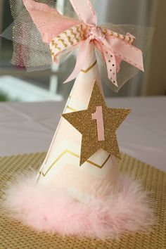 a pink and gold party hat with a number 1 on it sitting on top of a table