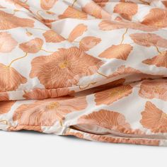 an orange and white flowered comforter on top of a bed with pink sheets