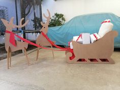 two cardboard reindeer sleighs with presents tied to them