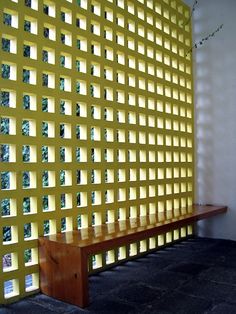 a wooden bench sitting in front of a wall with squares on it's sides