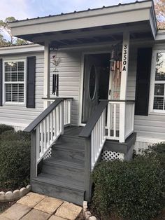 a small white house with black shutters and steps leading up to the front door