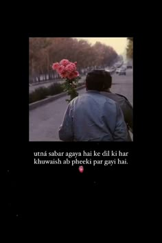 a man sitting on the side of a road with a flower in his lap and a quote written below