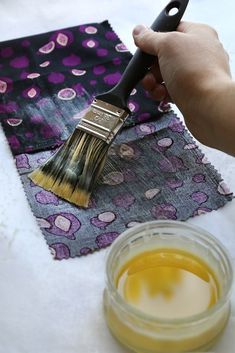 a person holding a paint brush over some fabric