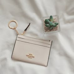 a card case and keychain sitting on top of a white bed next to a small cactus