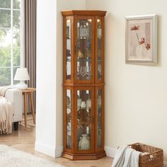 a corner cabinet with glass doors in a living room next to a rug and window