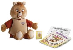 a teddy bear sitting next to a children's book and an open package for it